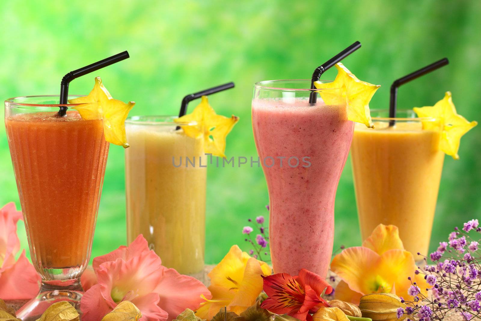 Fresh papaya, strawberry, pineapple and mango fruit juices and milkshakes decorated with flowers (Selective Focus, Focus on the papaya and strawberry juices in the front)