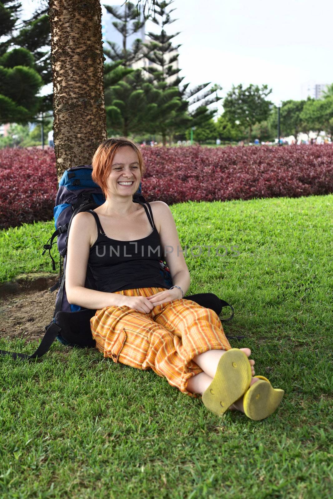 Young Caucasian woman with backpack leaning against a tree in a park in Miraflores, Lima, Peru (Selective Focus, Focus on the face of the woman)