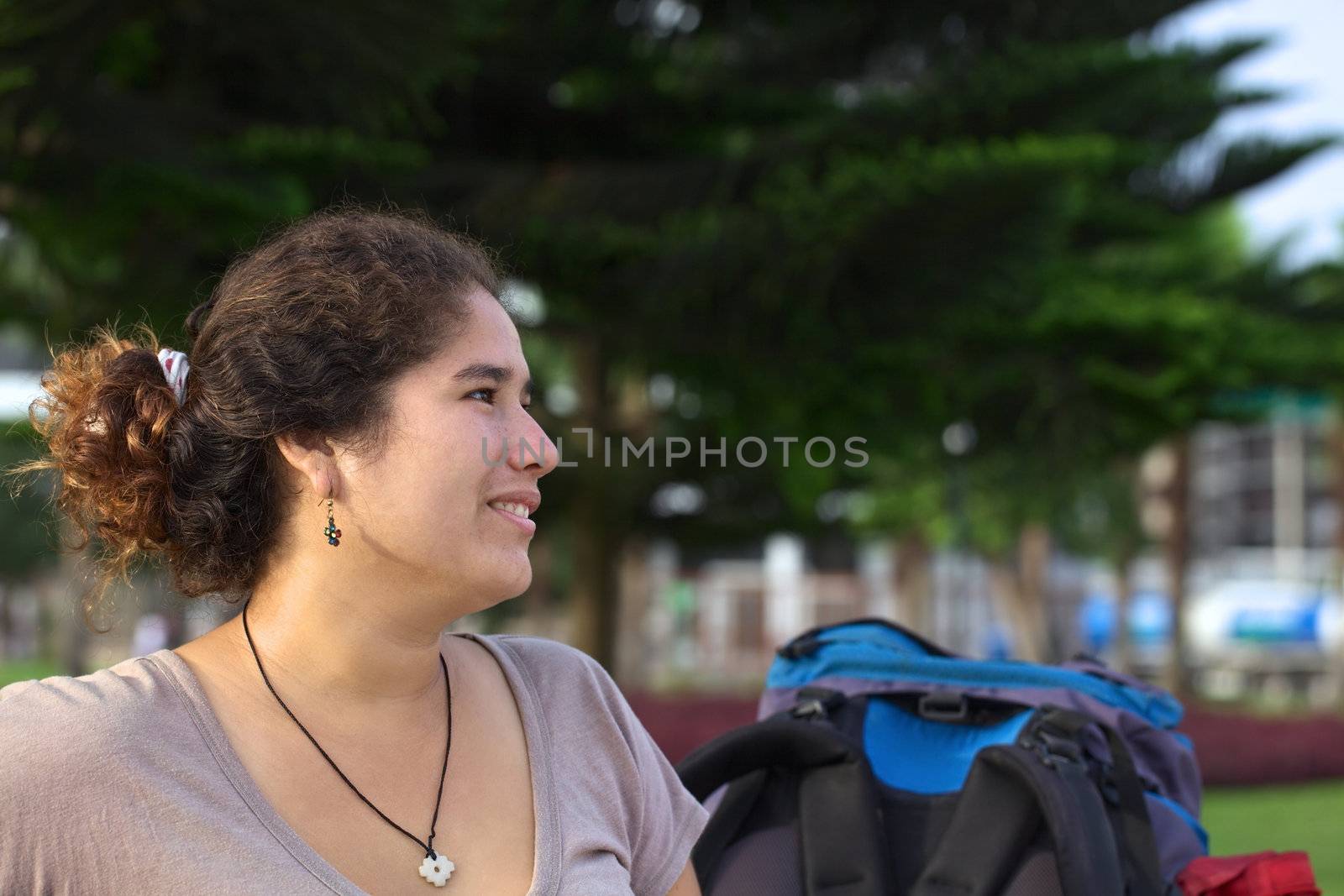 Young smiling Peruvian woman with backpack in park (Selective Focus, Focus on the face of the woman)