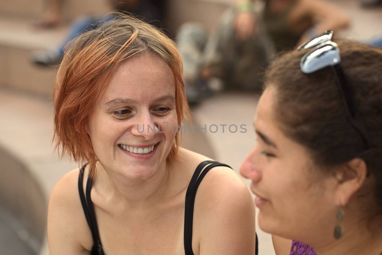 Young Caucasian woman talking to a young Peruvian friend (Selective Focus, Focus on the eyes of the Caucasian woman) 