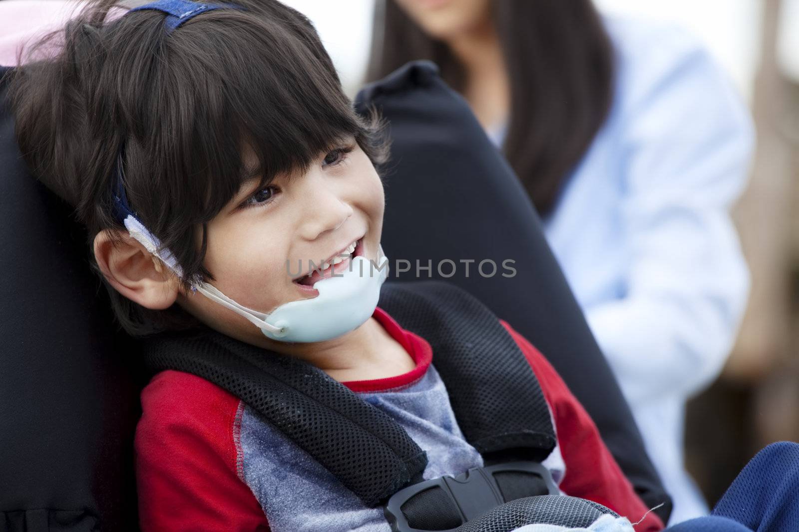 Happy five year old disabled boy in wheelchair and protective gear