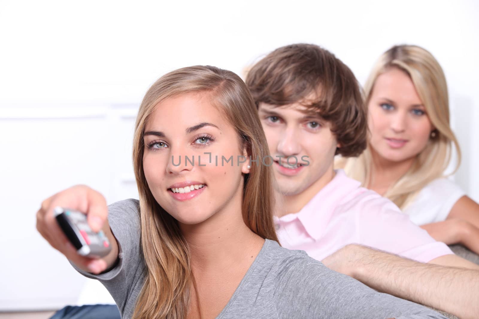 Three teenagers watching television together by phovoir