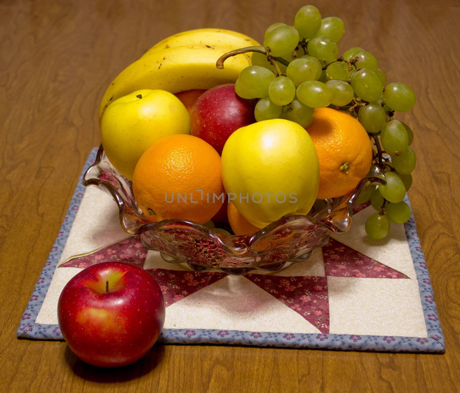 Bowl of fresh fruit with one apple outside.