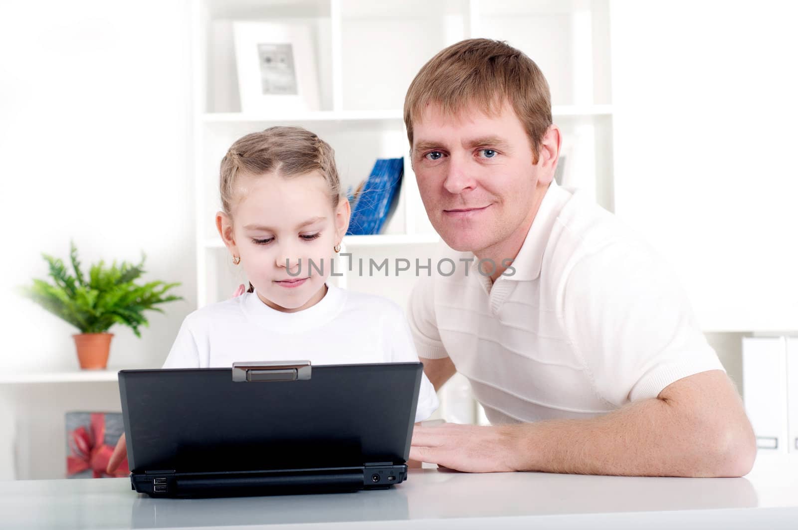 Father and daughter are working together for a laptop at home