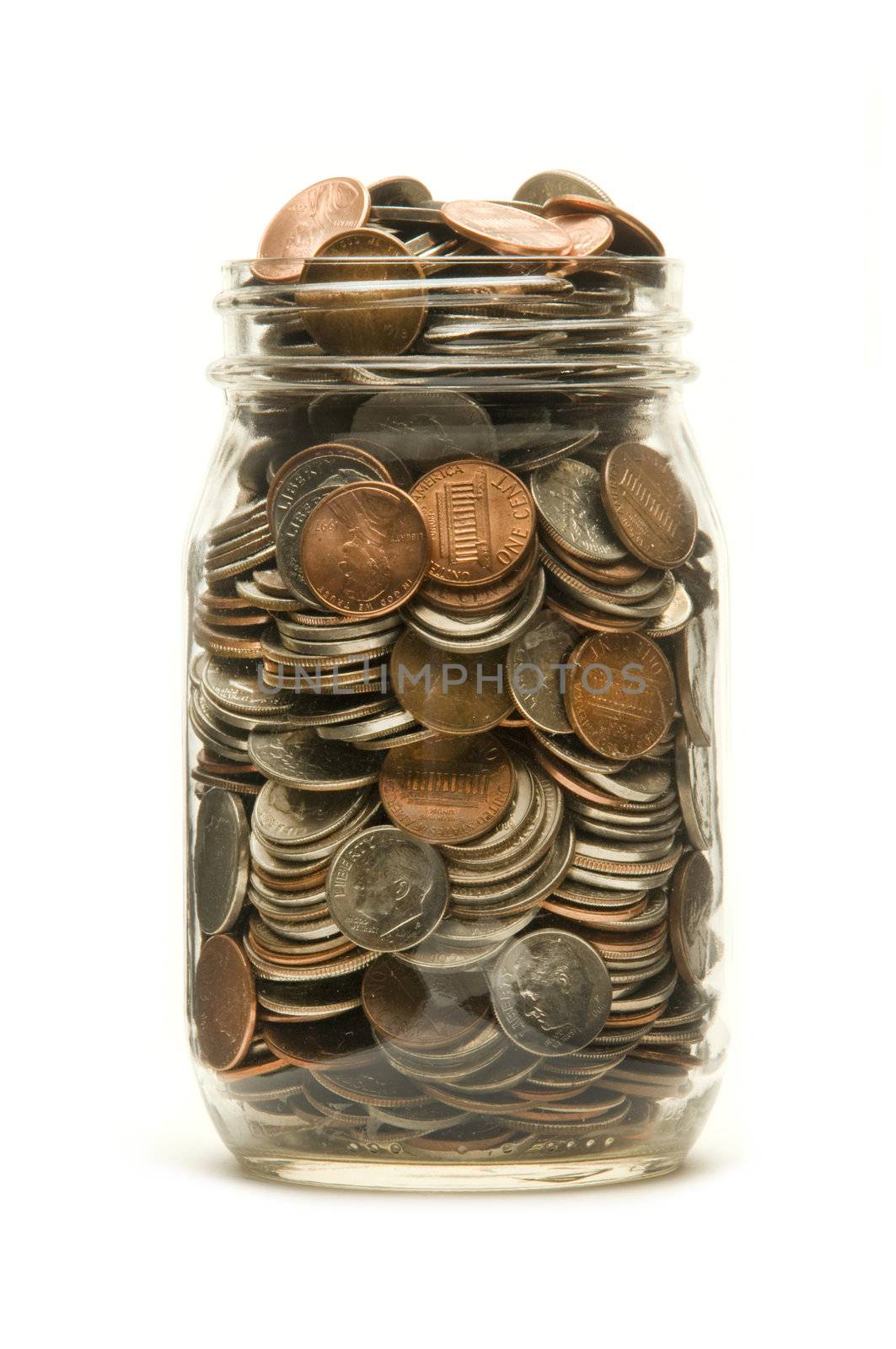 Glass jar almost overflowing with American coins against a white background