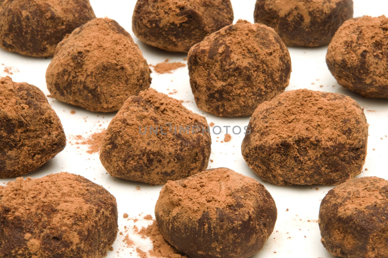 Bunch of chocolate truffles with cocoa powder on a white surface