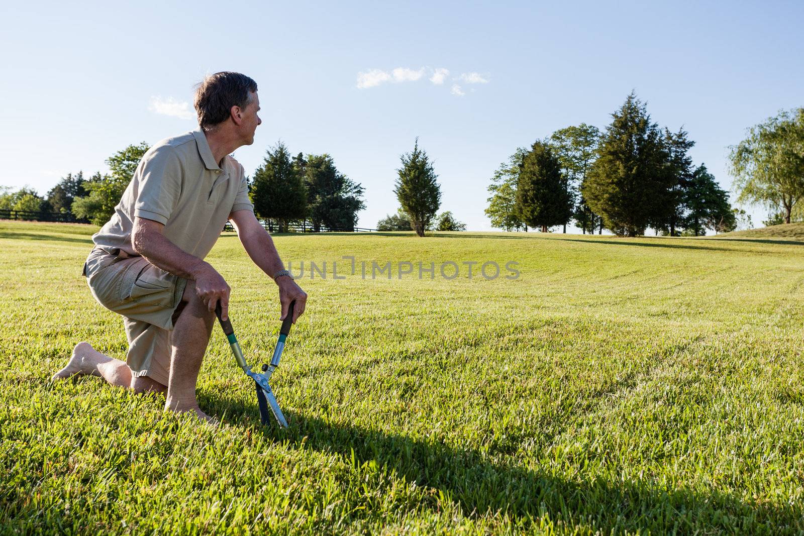 Senior man cutting grass with shears by steheap