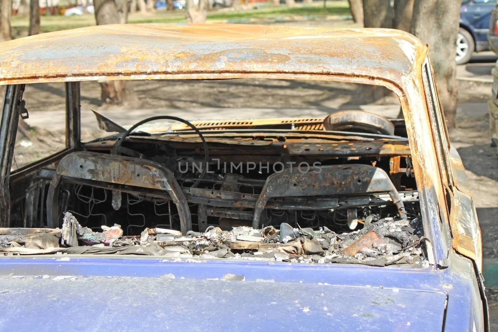 A fully burned car in the street