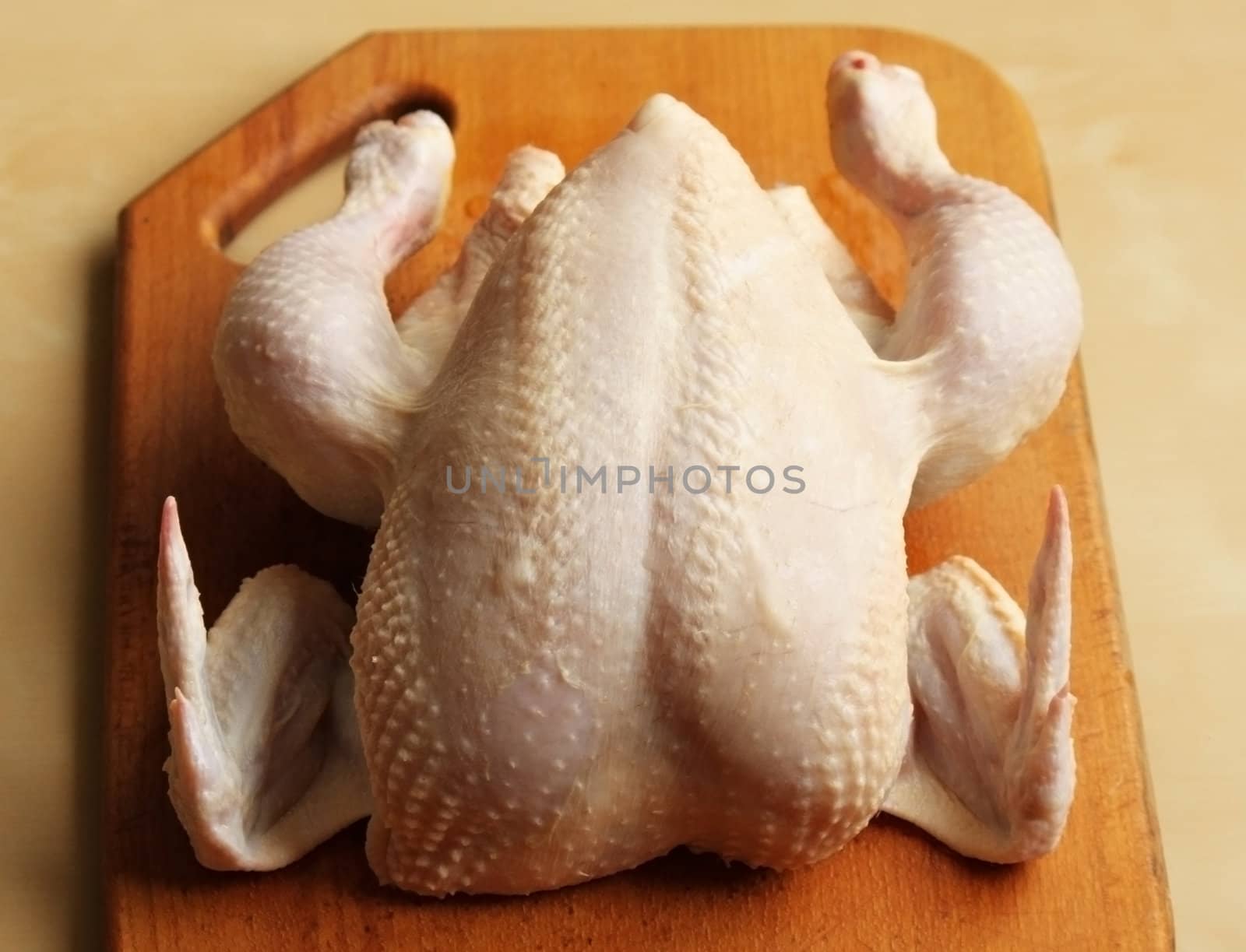 Whole raw chicken on the chopping board
