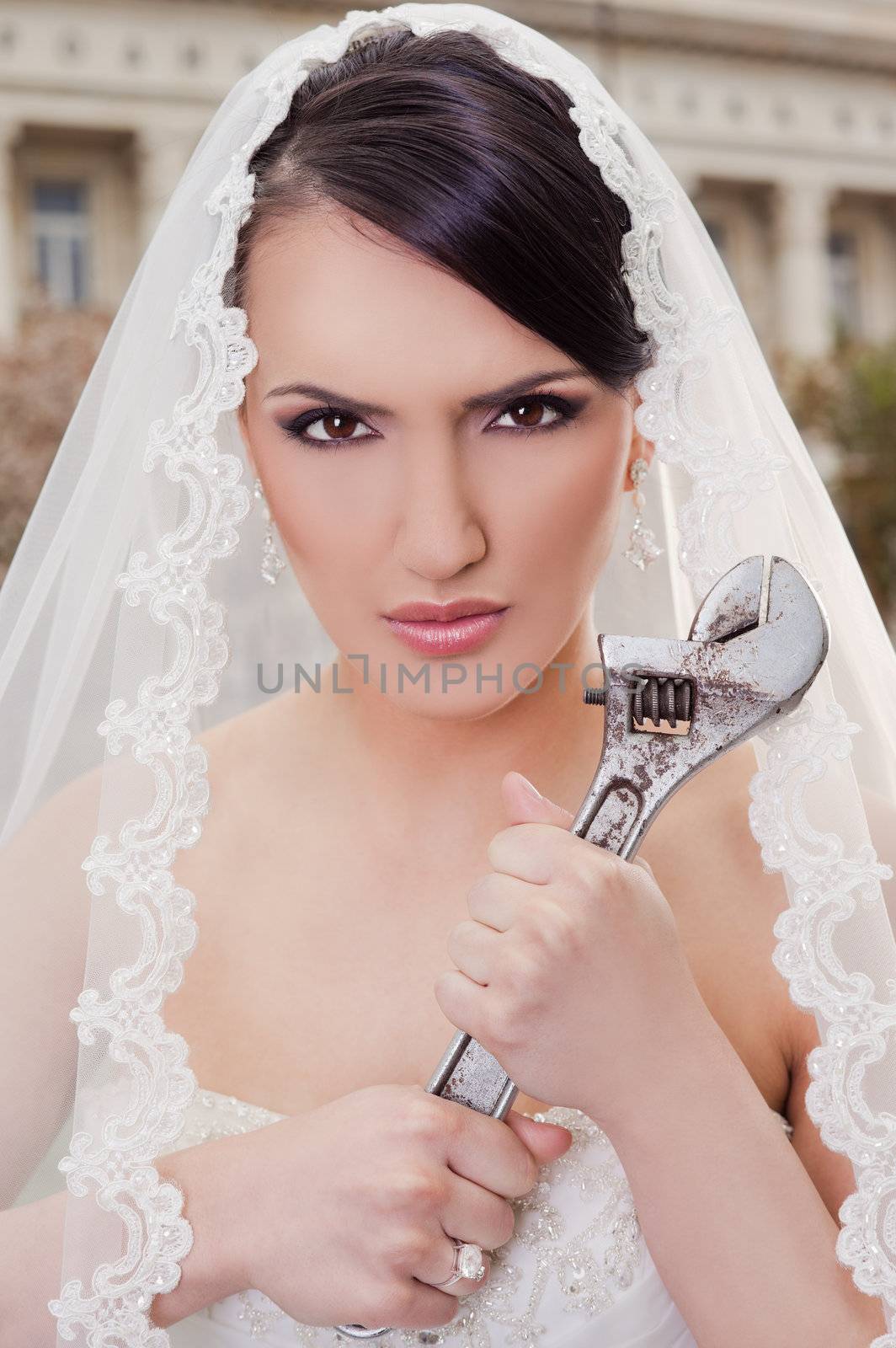 Close-up of angry bride holding monkey wrench, lookin at camera
