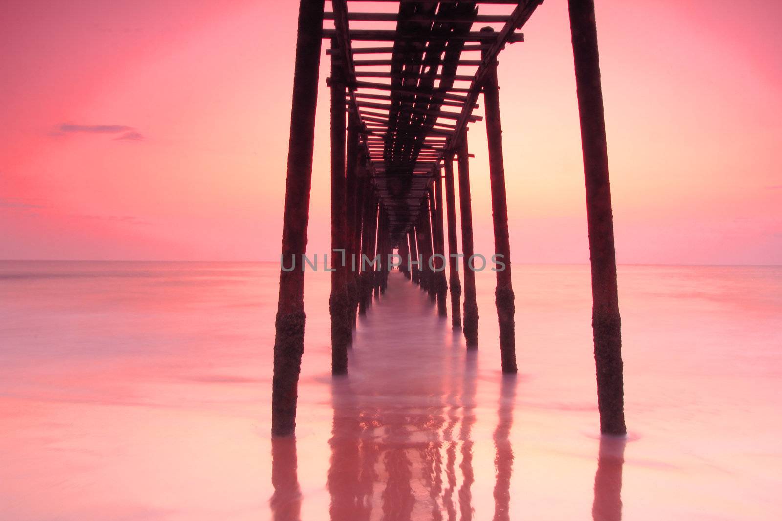 Long exposure wood bridge to the sea over sunset