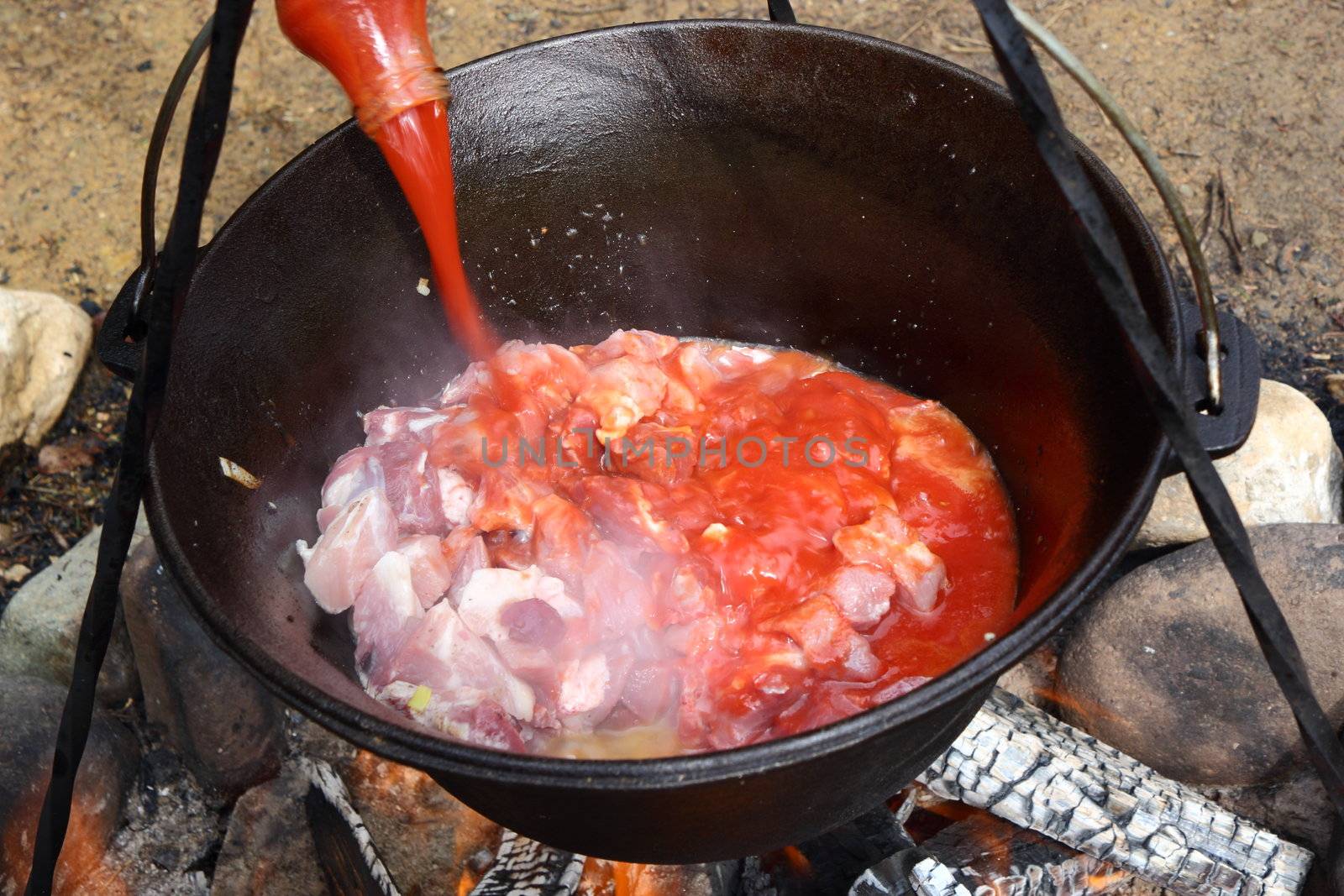 preparing osso buco outdoor in traditional cauldron