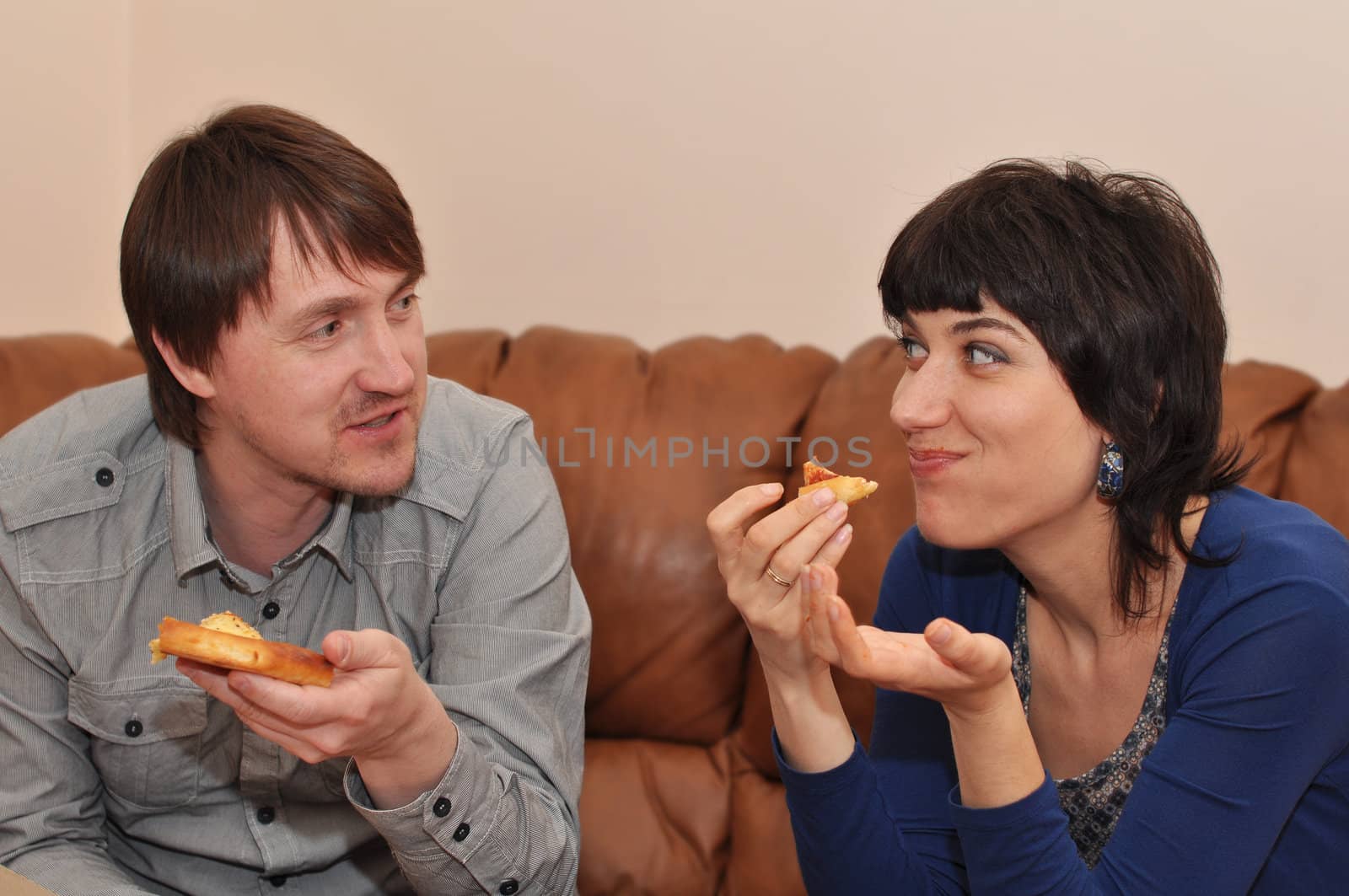 Married couple eating pizza and smiling