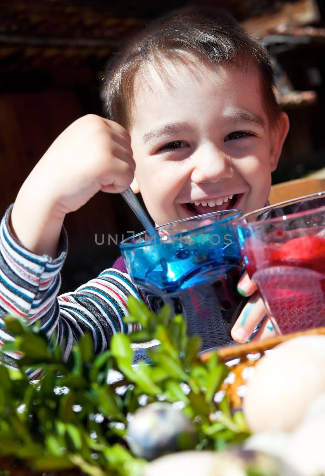Happy young boy behind glasses with dye painting easter eggs
