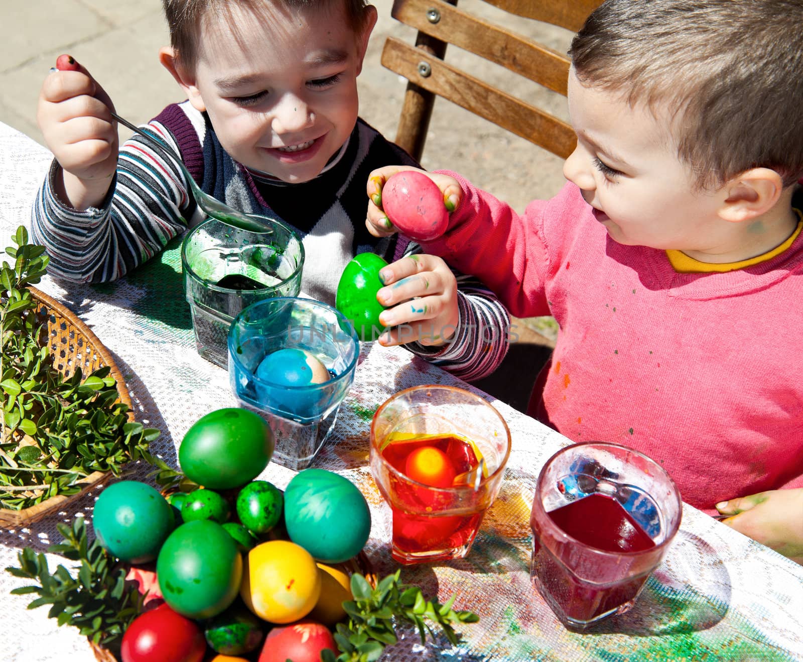Two sweet little boys having fun dyeing eggs for easter