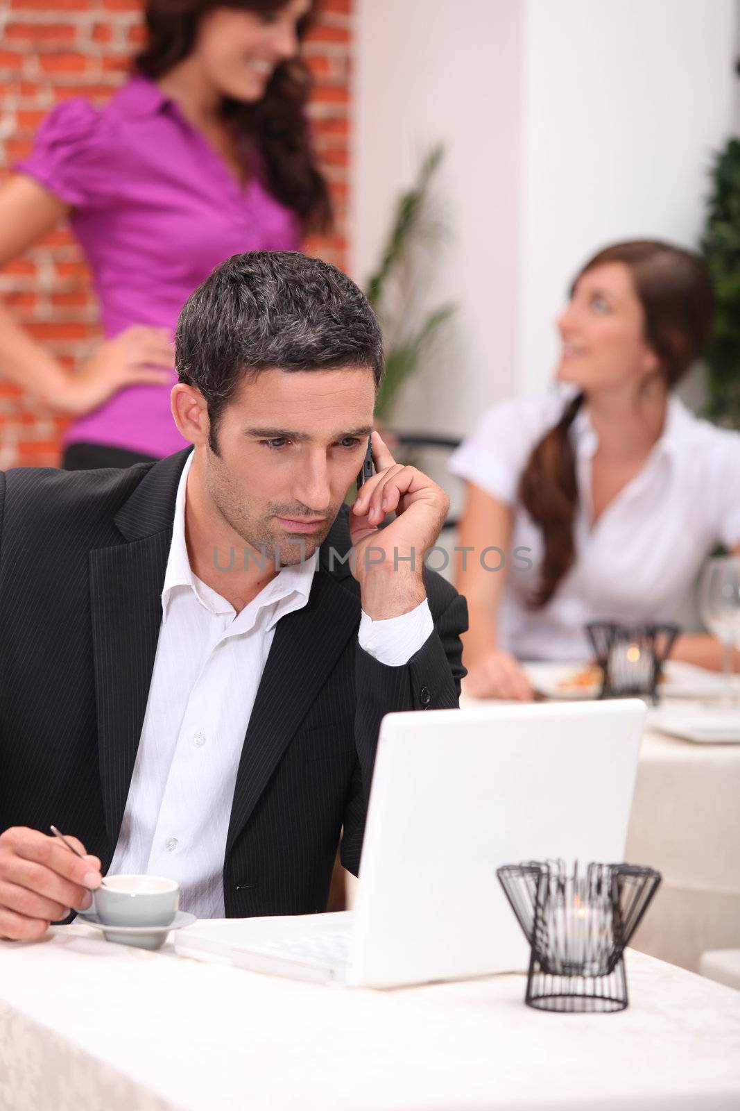 Businessman in a restaurant with a laptop by phovoir