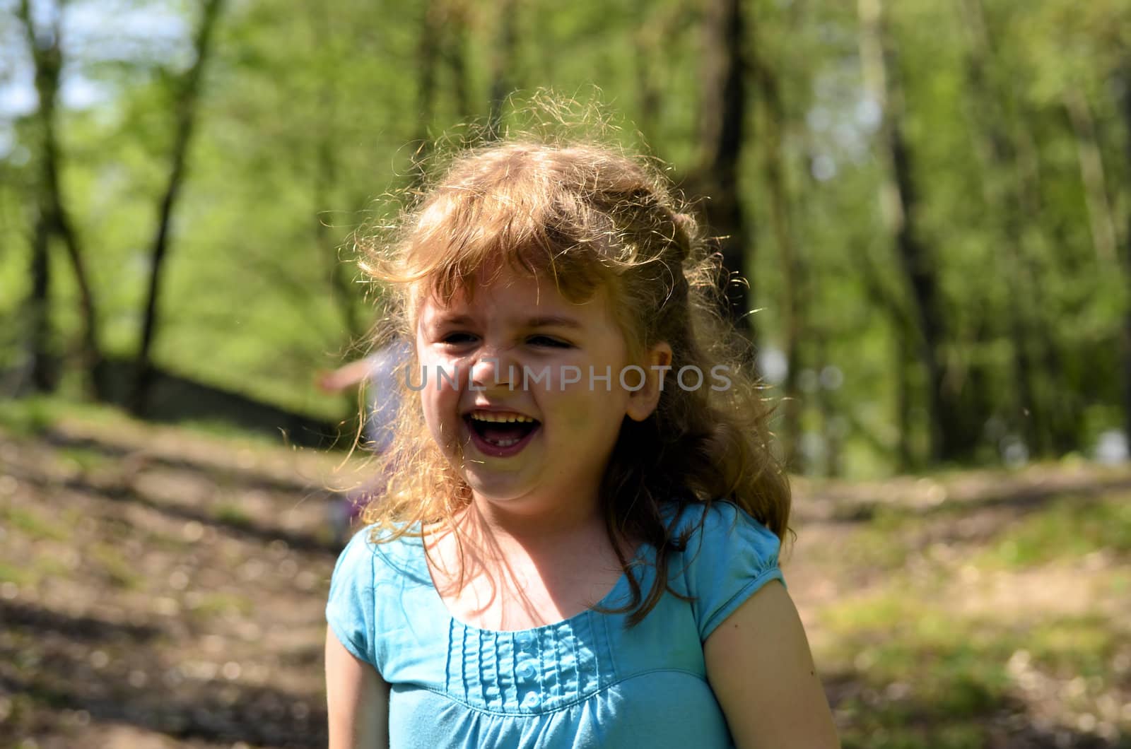 The photo shows a happy, smiling and joyful girl in the park.