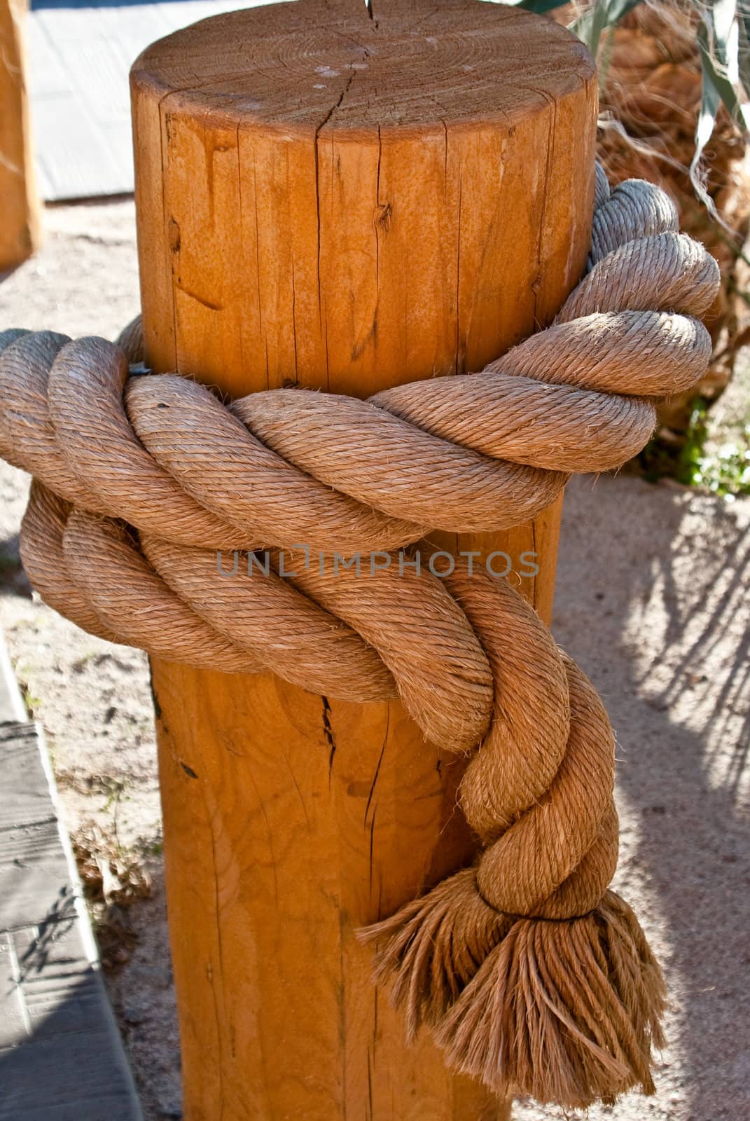 Large nautical rope tied on wooden post