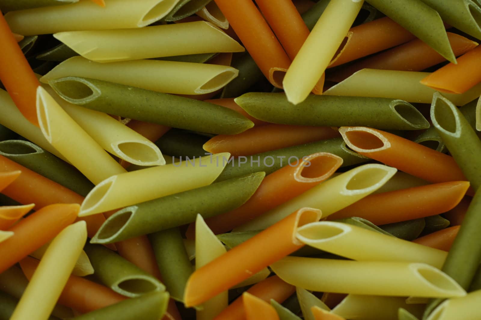 uncooked spaghetti tubes colored background of macro