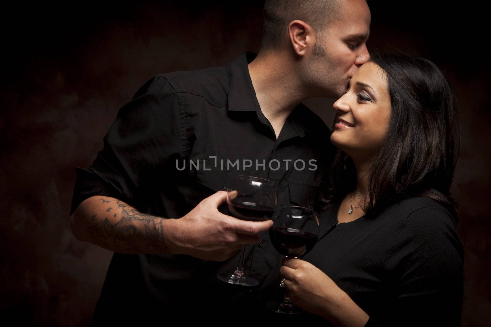 Happy Mixed Race Couple Flirting and Holding Wine Glasses on a Dark Background.