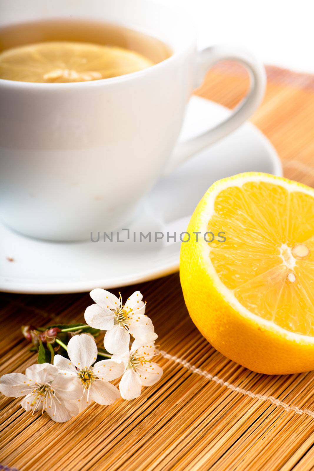 Tea in white cup with lemon and cherry flower