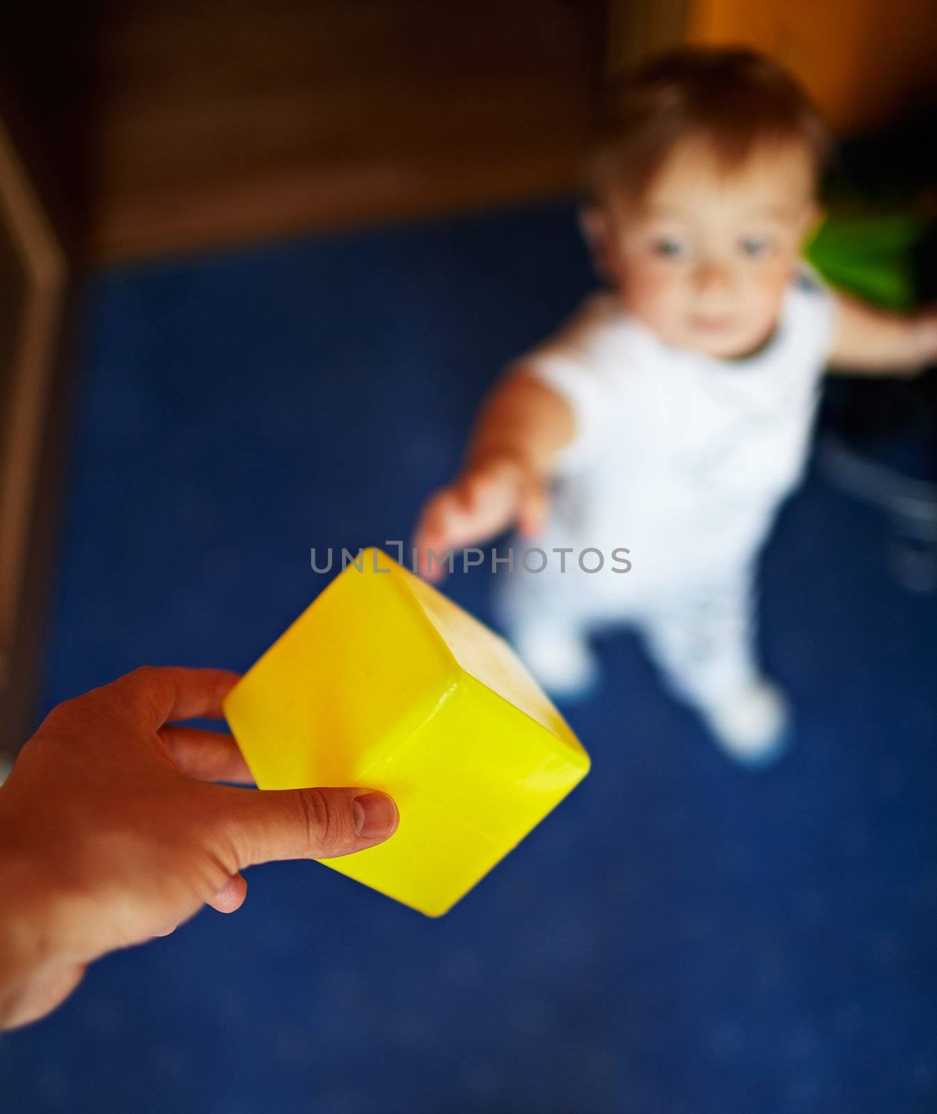 Little handsome boy takes the yellow cube. Shallow dof, focus is on the cube.