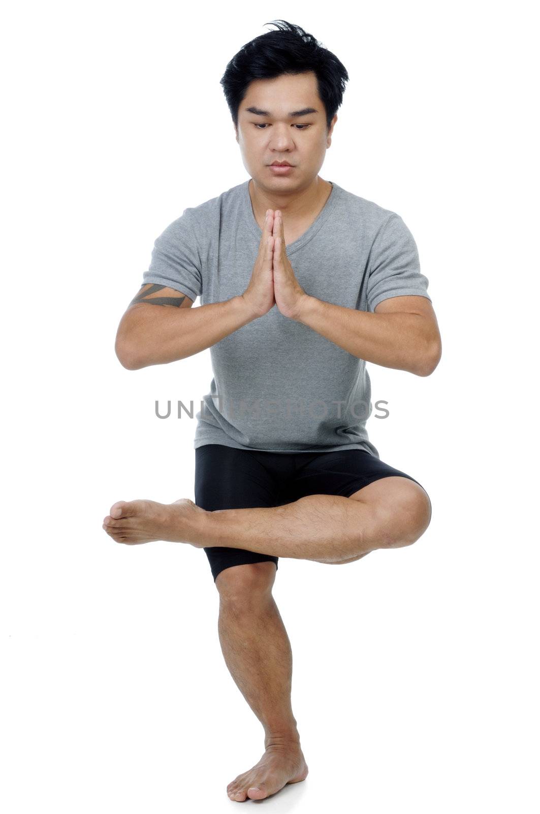 Portrait of a handsome Asian man doing yoga stance over white background.
