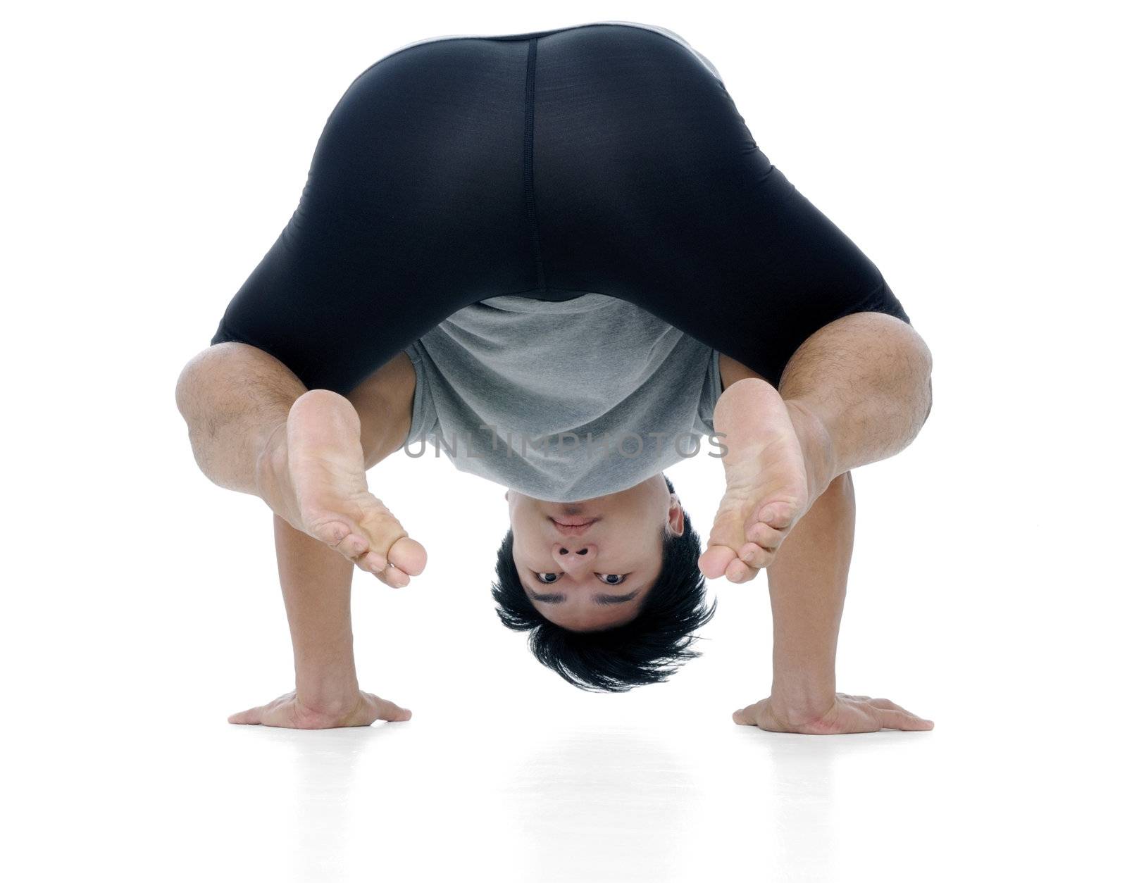 Portrait of a handsome young Asian man doing yoga exercise over white background.