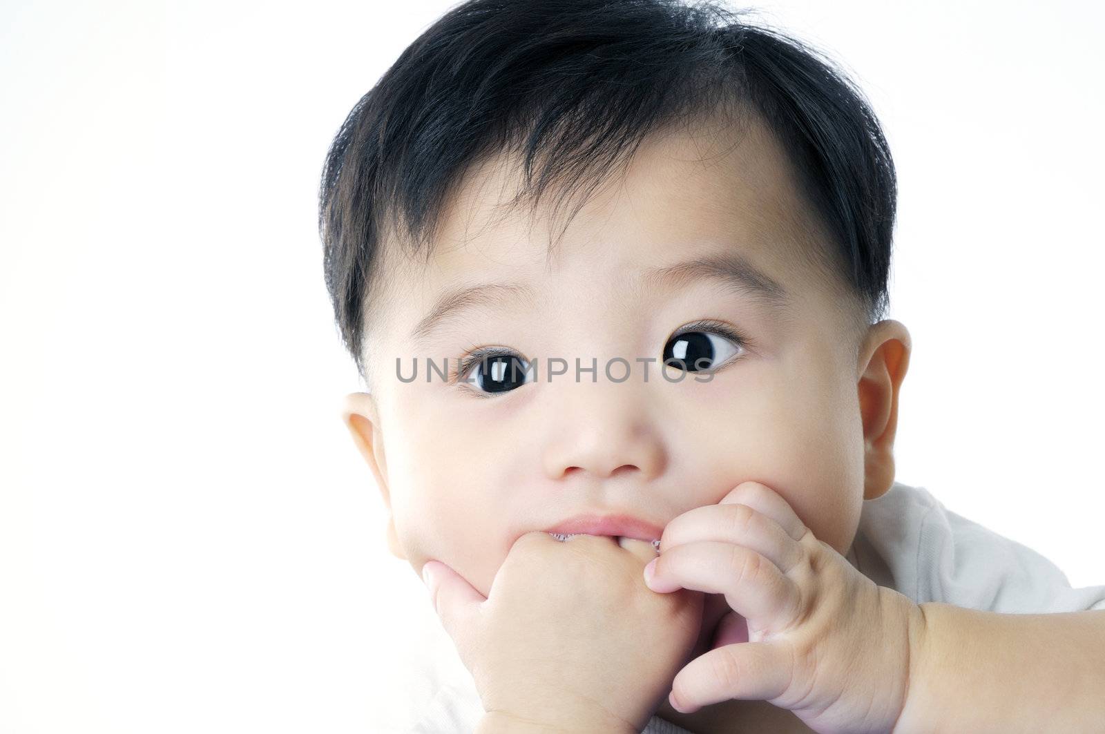 Closeup portrait of an adorable infant baby sucking his hand over white background.