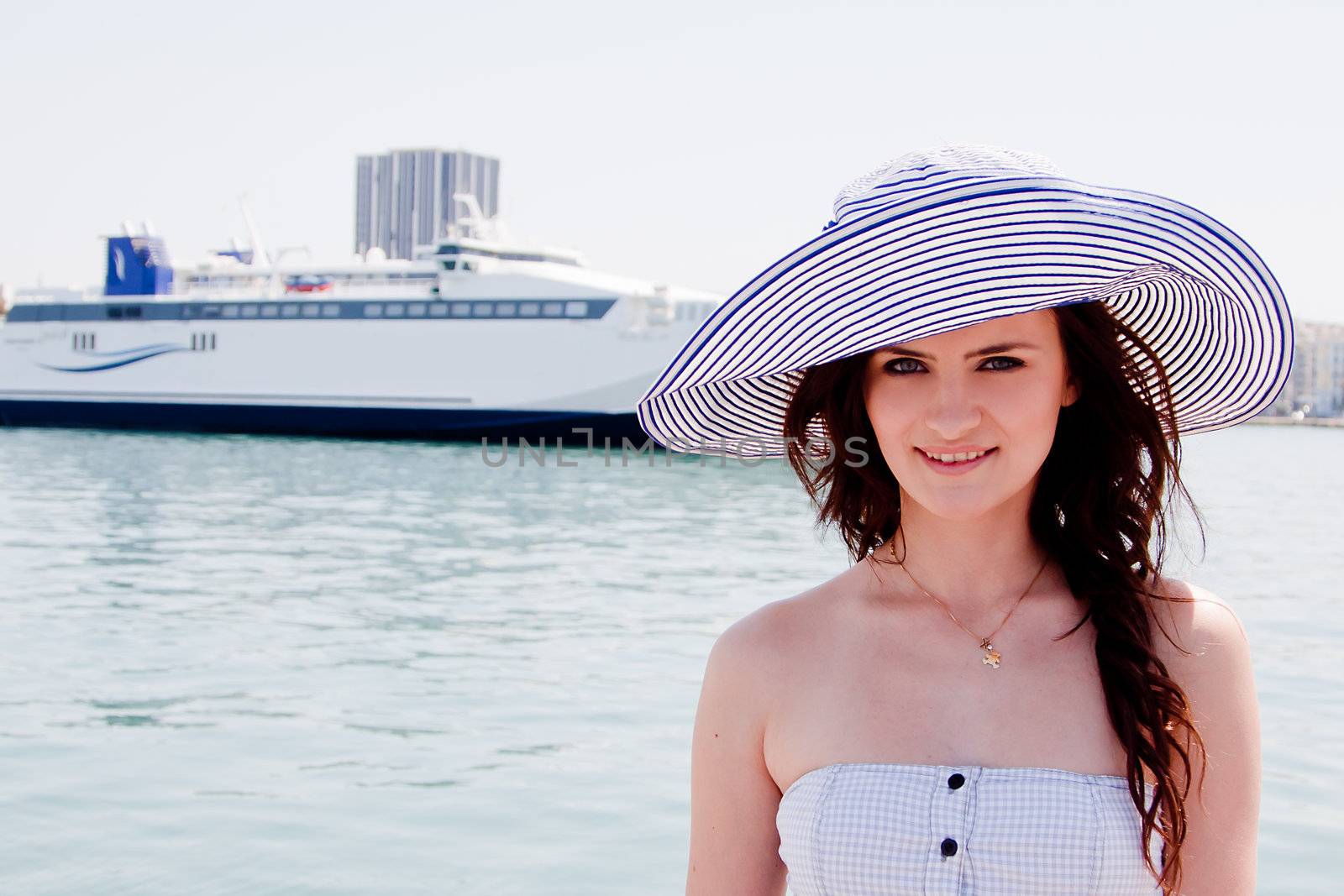 Portrait of a young and beautiful girl in the background of a large ocean liner