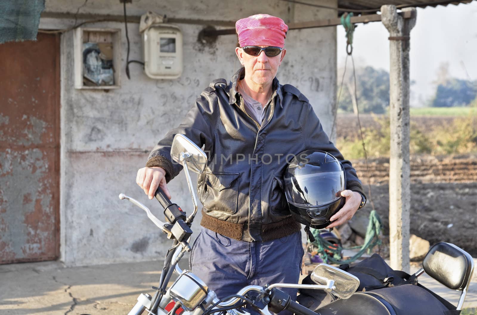Caucasian motor cyclist touring India outs a shack in Gujarat hinterlands
