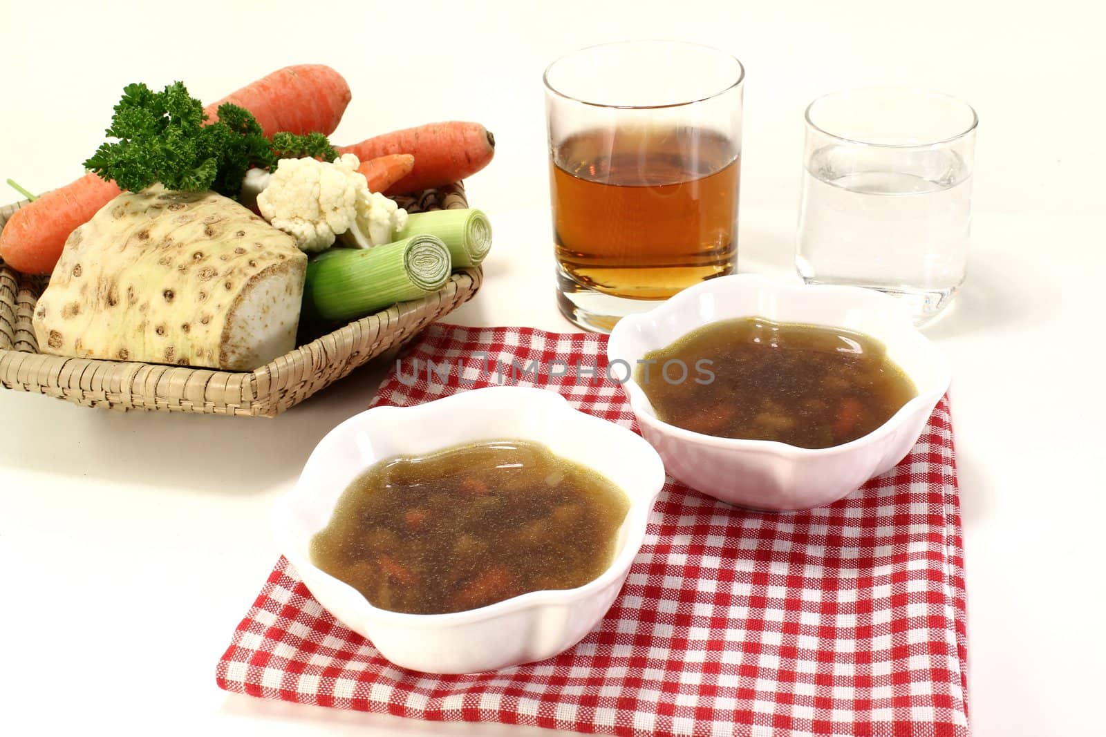 Beef consomme with soup vegetables on a napkin on light background