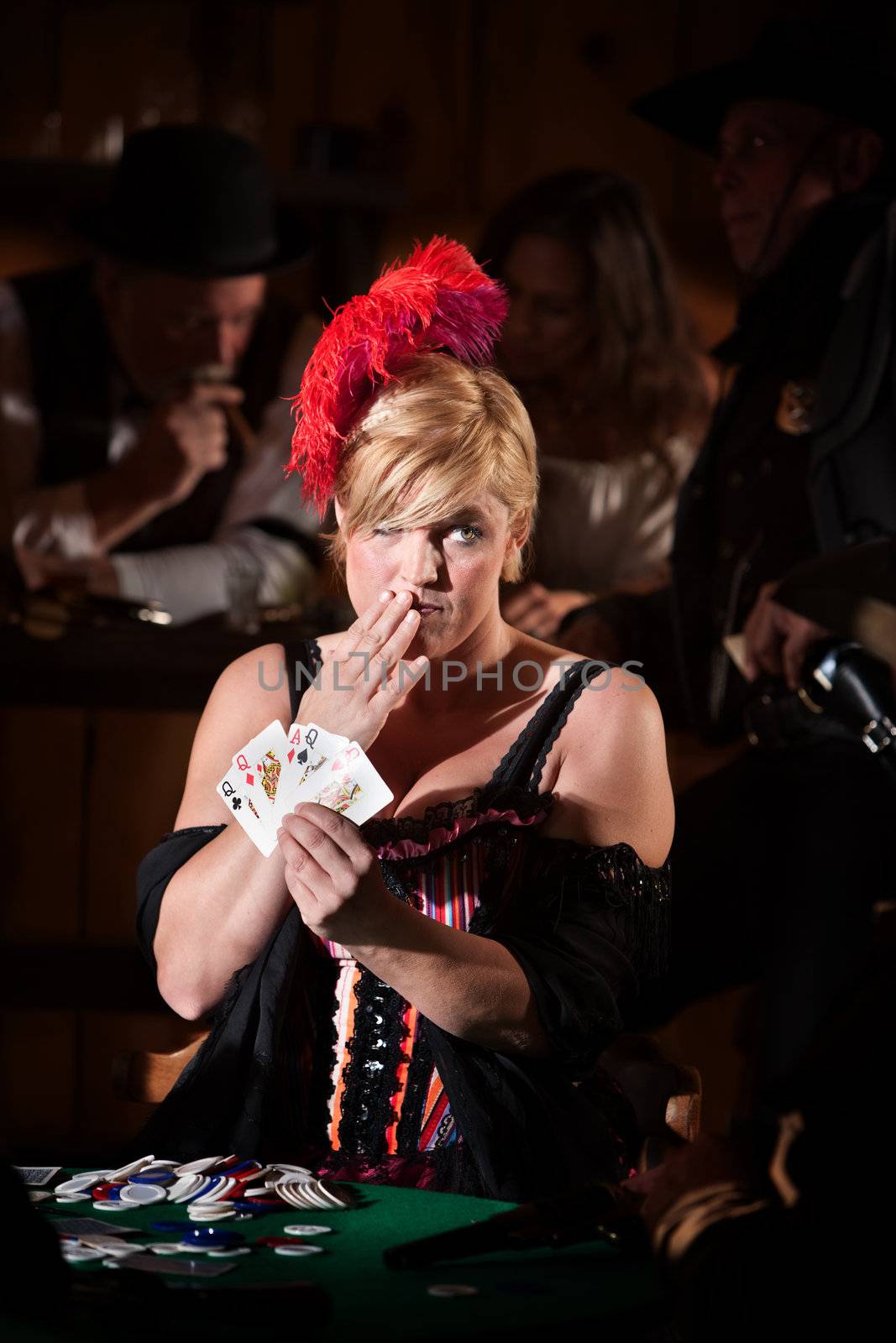 Pretty showgirl with hand over mouth and playing cards
