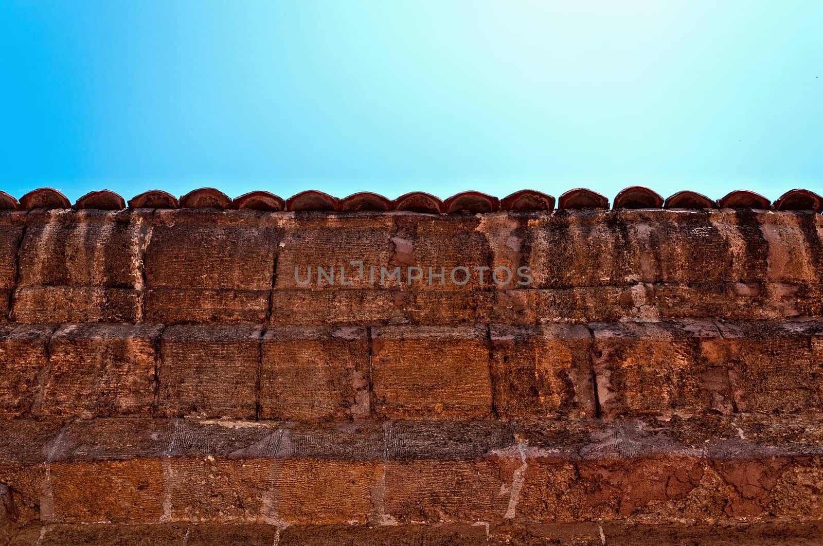 A fragment of an old weathered fence with a tiled cover.