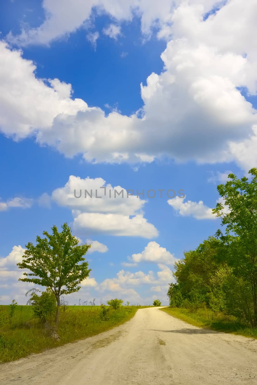 Cloudscape over rural road paved with limestone in springtime