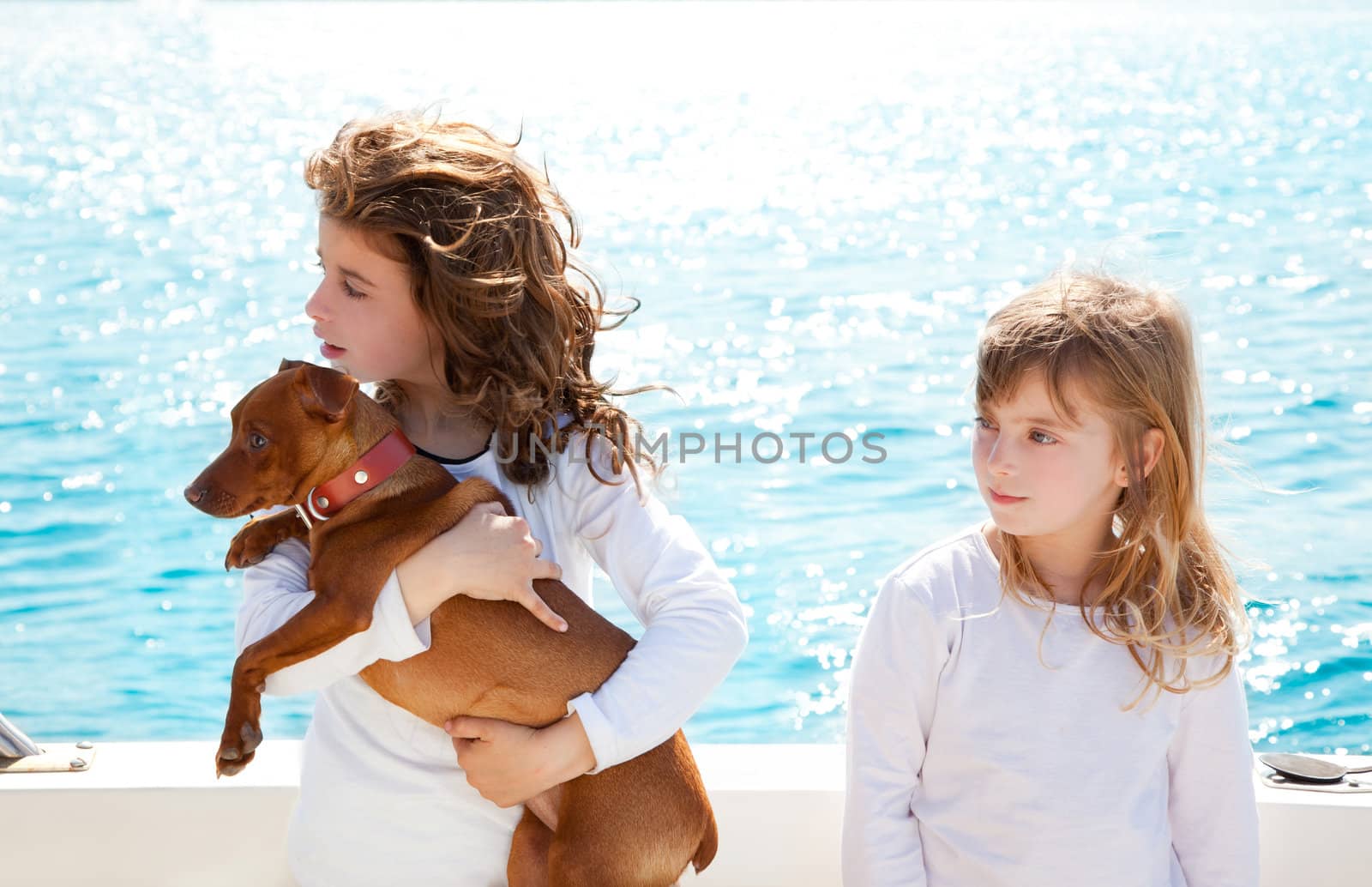 sister kid girls with dog mini pinscher on the sea view from a boat