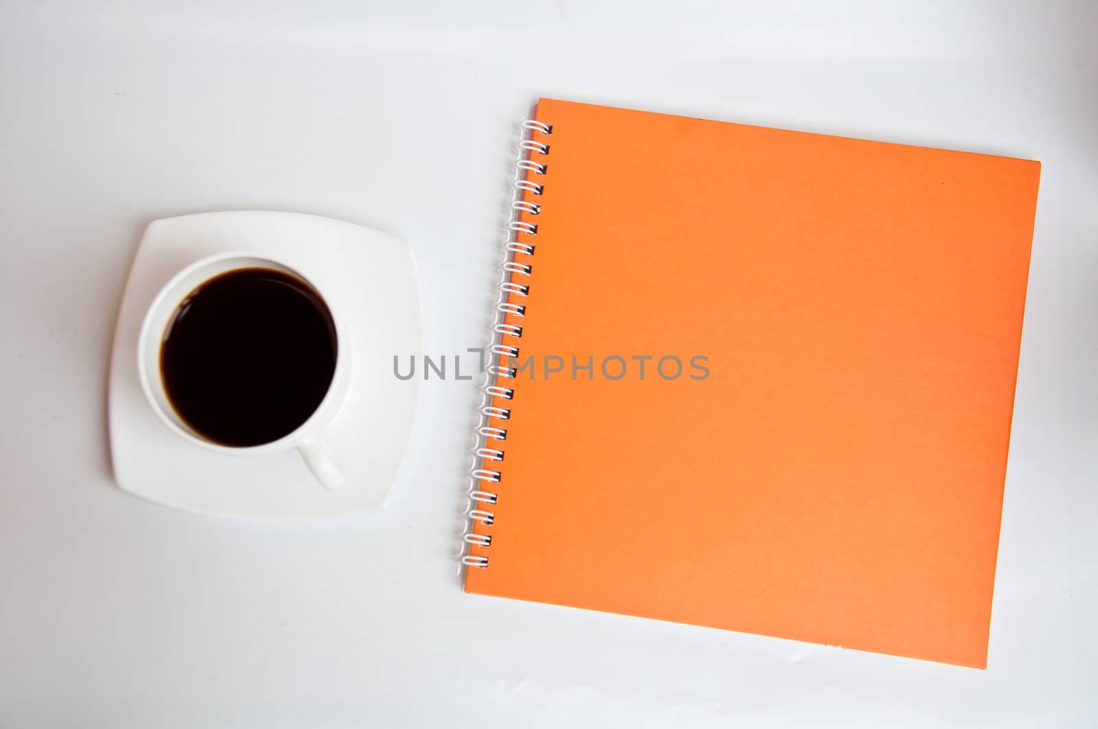 black coffee and orange notebook on white background