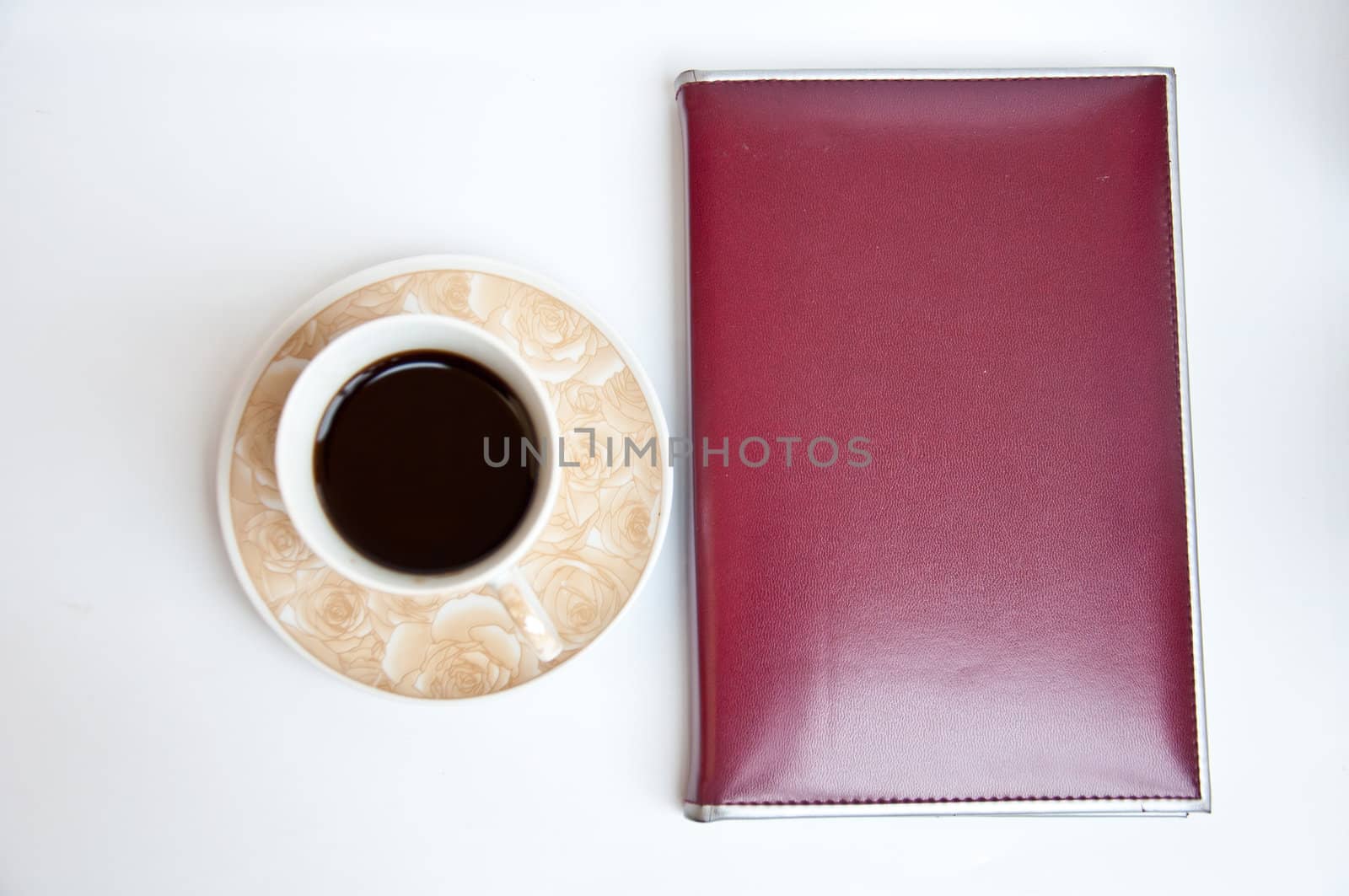 brown notebook and black coffee on white background