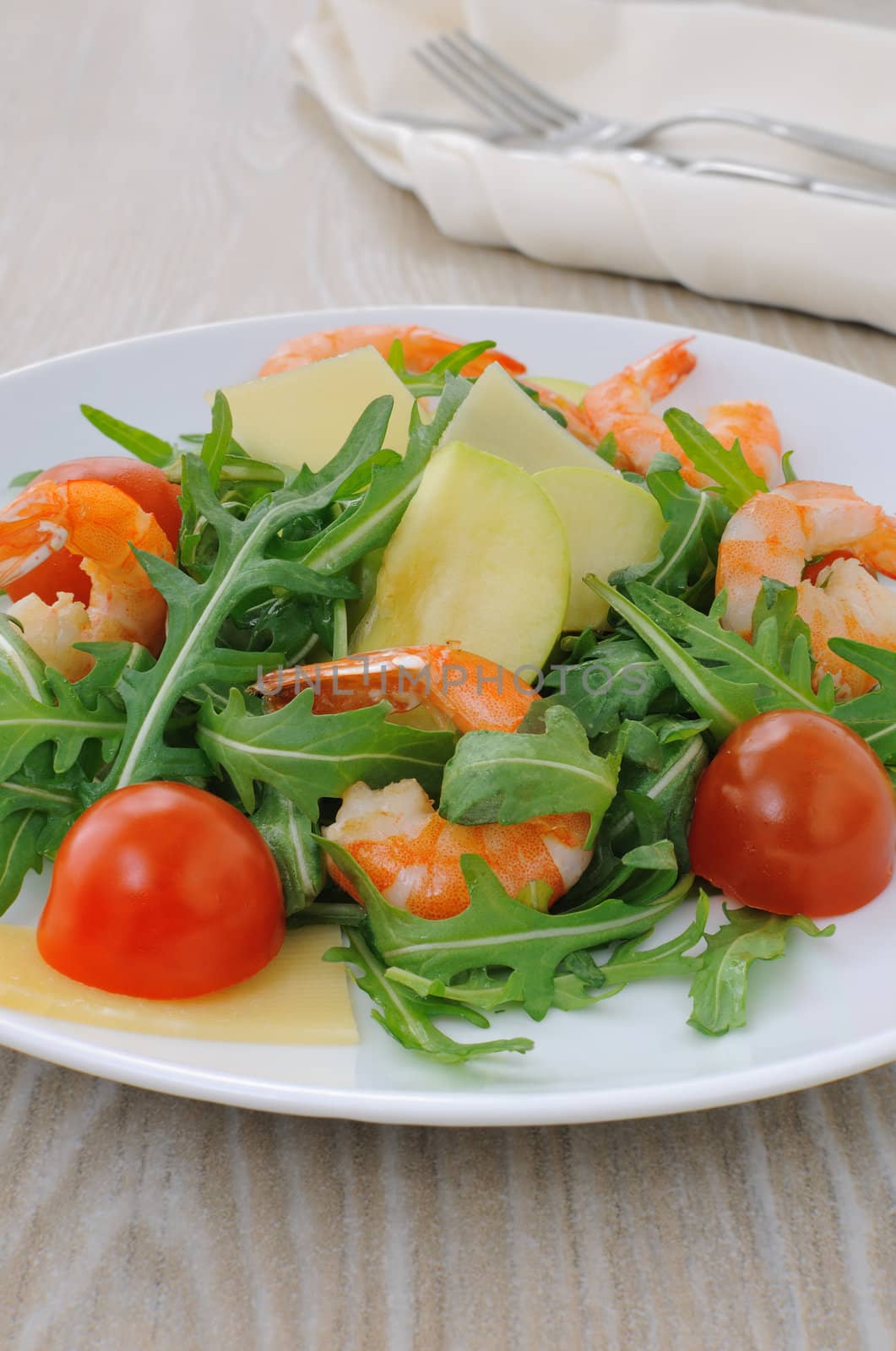 Salad with arugula and cherry tomatoes with shrimp, slices of apple and parmesan