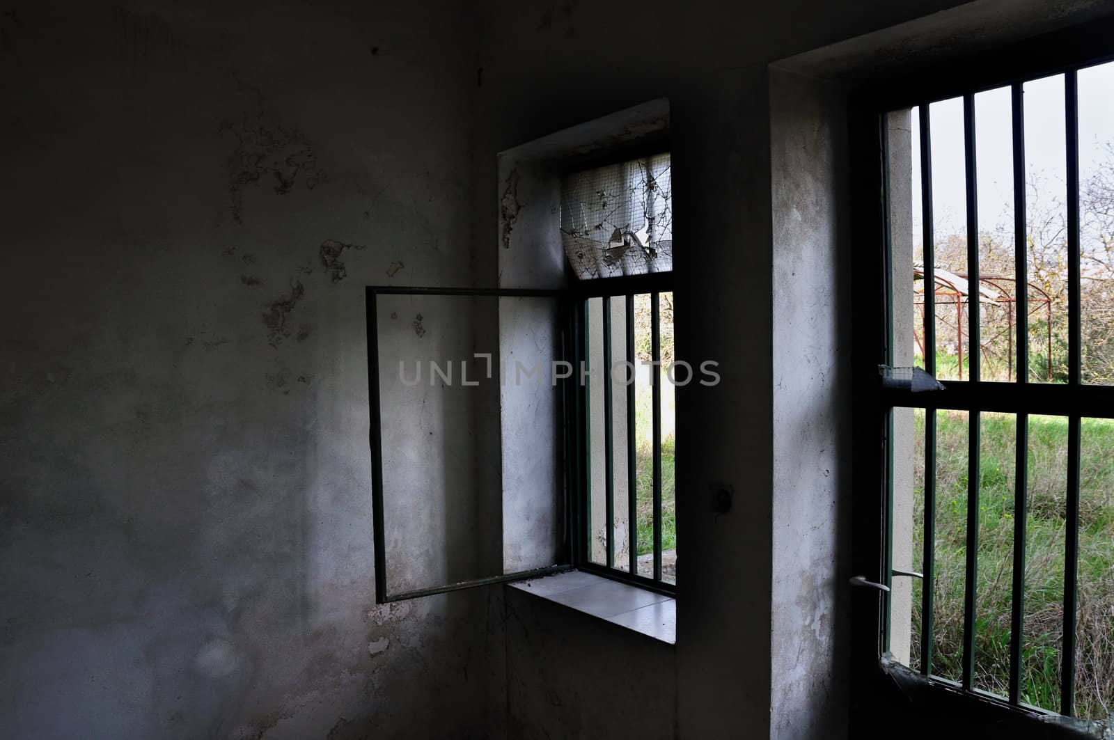 Barred door and windows in abandoned house interior.
