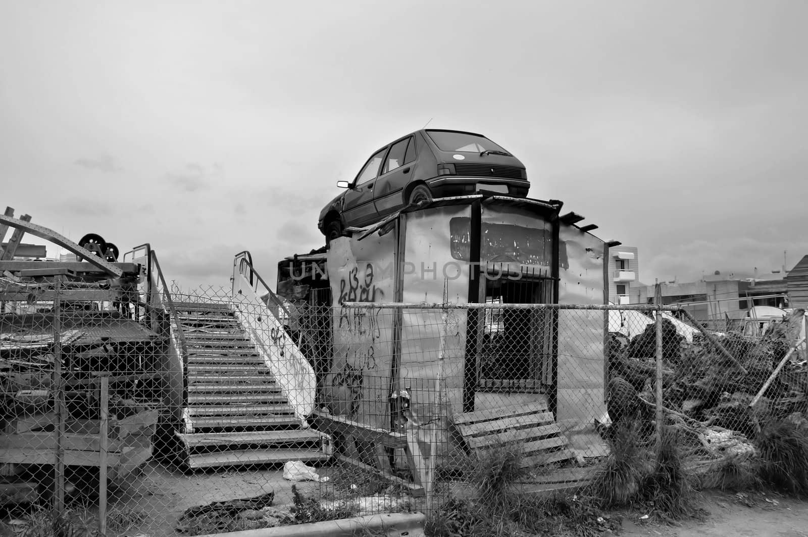 Rusty car and scrap metal at a junkyard. Black and white.