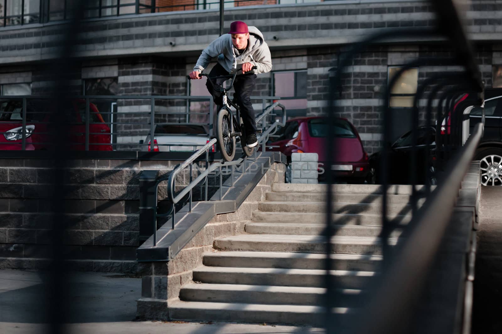 Biker doing double peg grind down the hand rail over the stairs