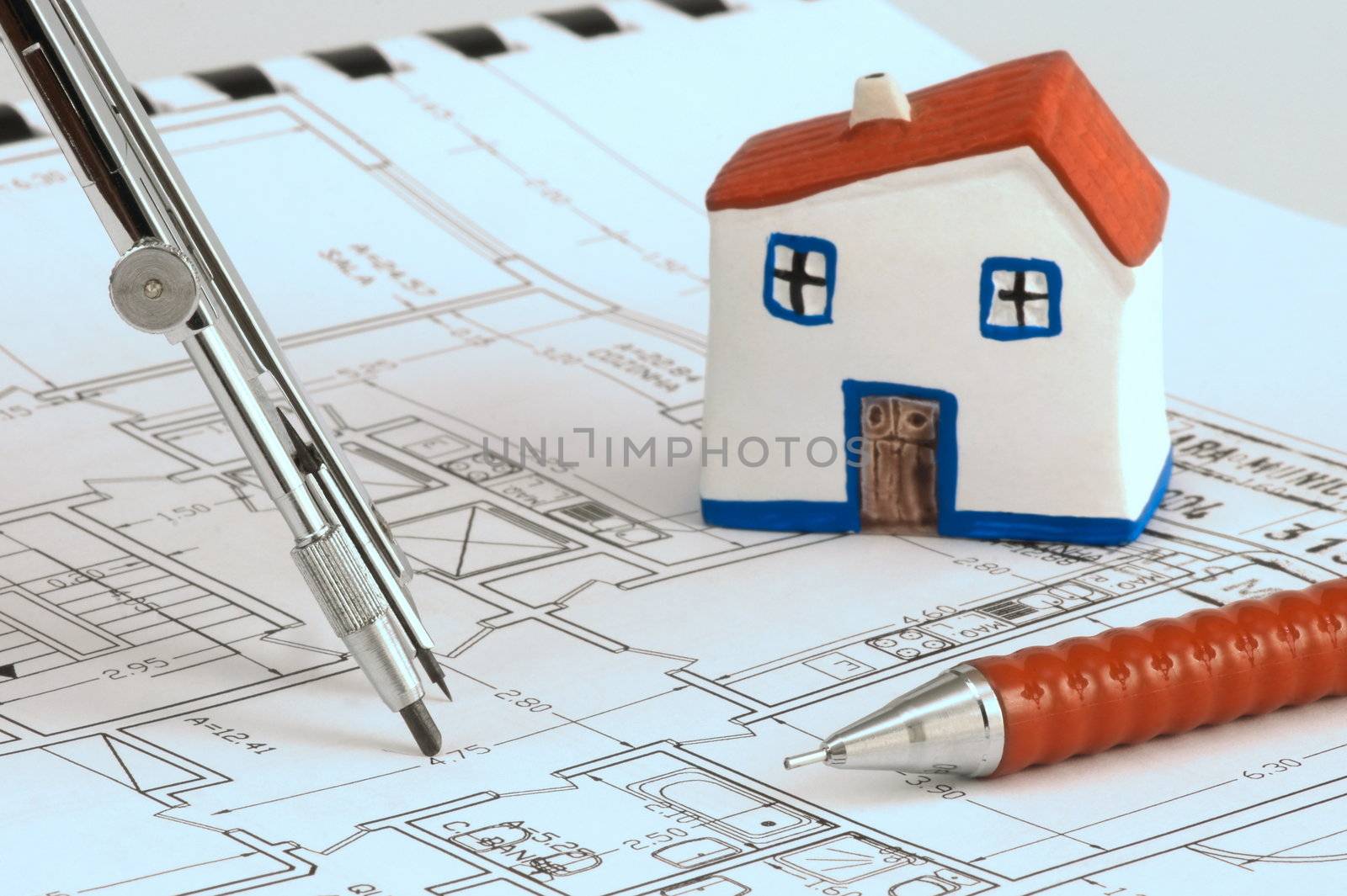 Blue print with miniature model house, compass and pencil