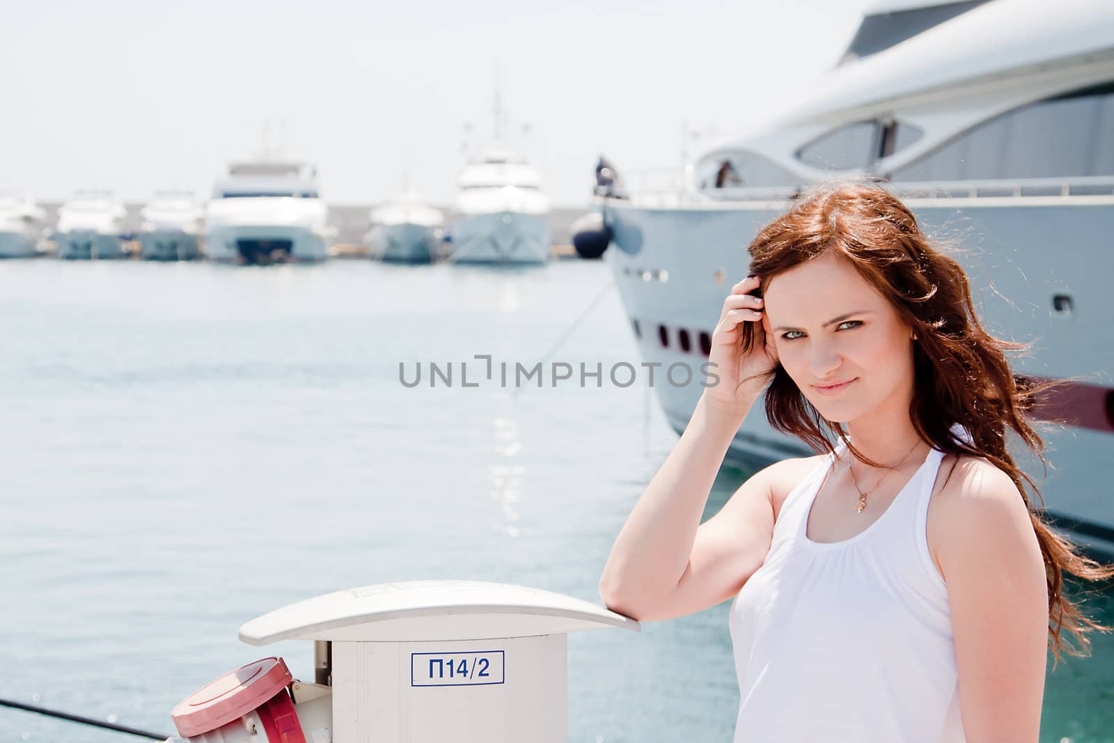 Photo of a young and beautiful girl against the backdrop of yachts in the port