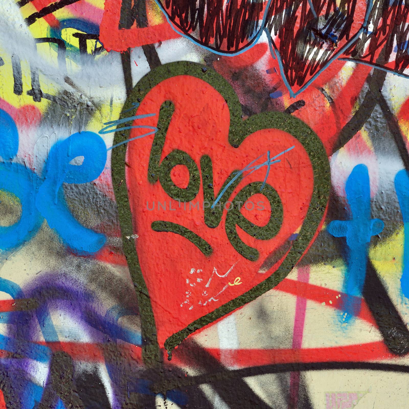 Heart graffiti over messy tagged urban wall background.