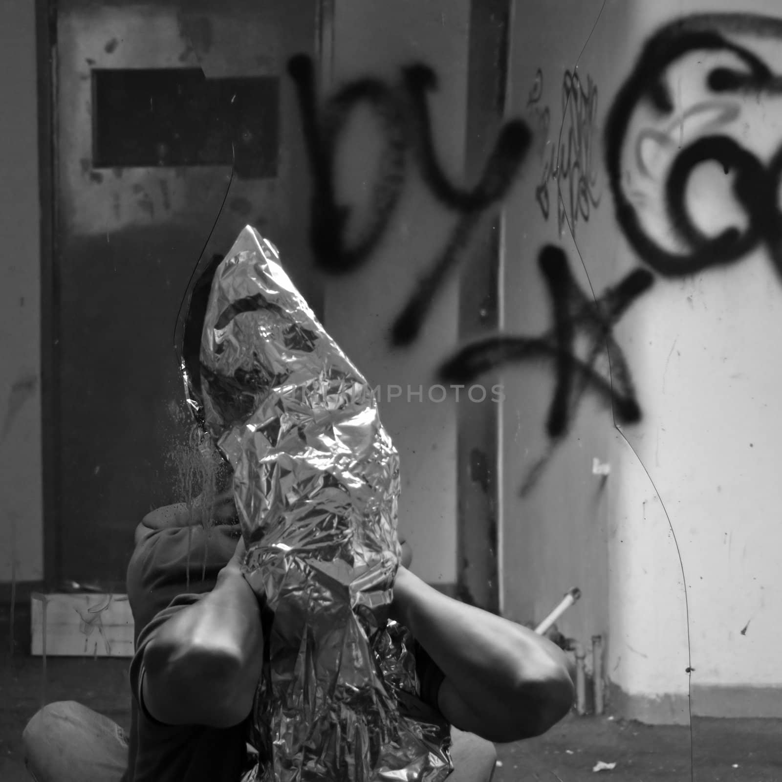 Obscured man and broken mirror in abandoned interior. Black and white.