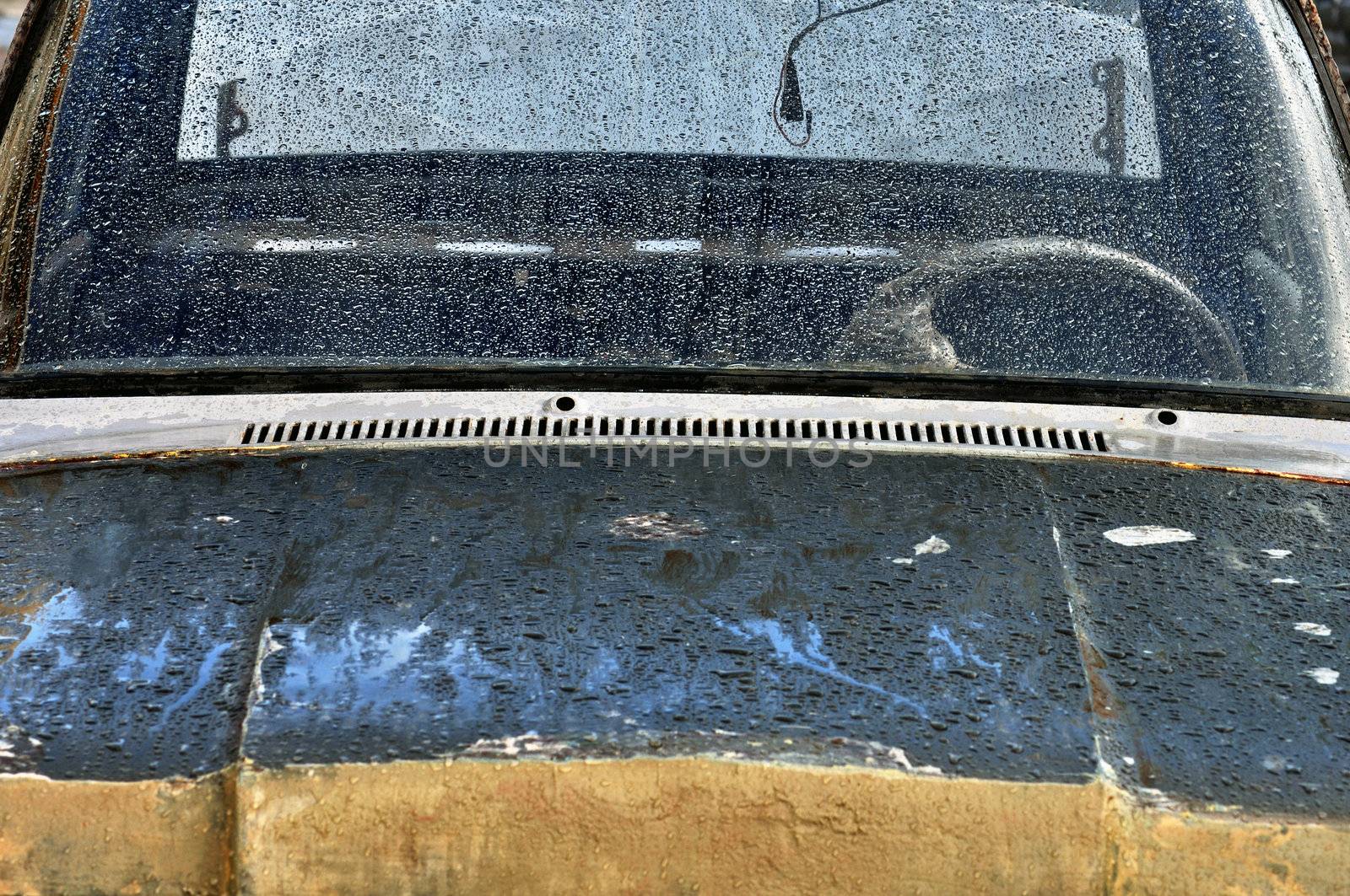 Vintage car scraped hood and rain covered windscreen.
