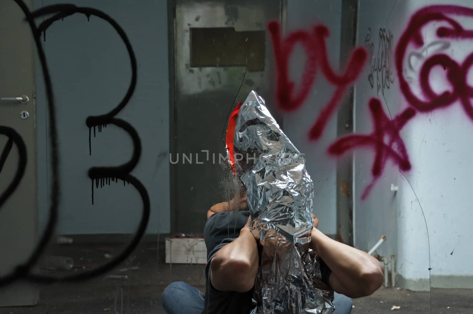 Distorted man emerging through broken glass mirror in abandoned interior.