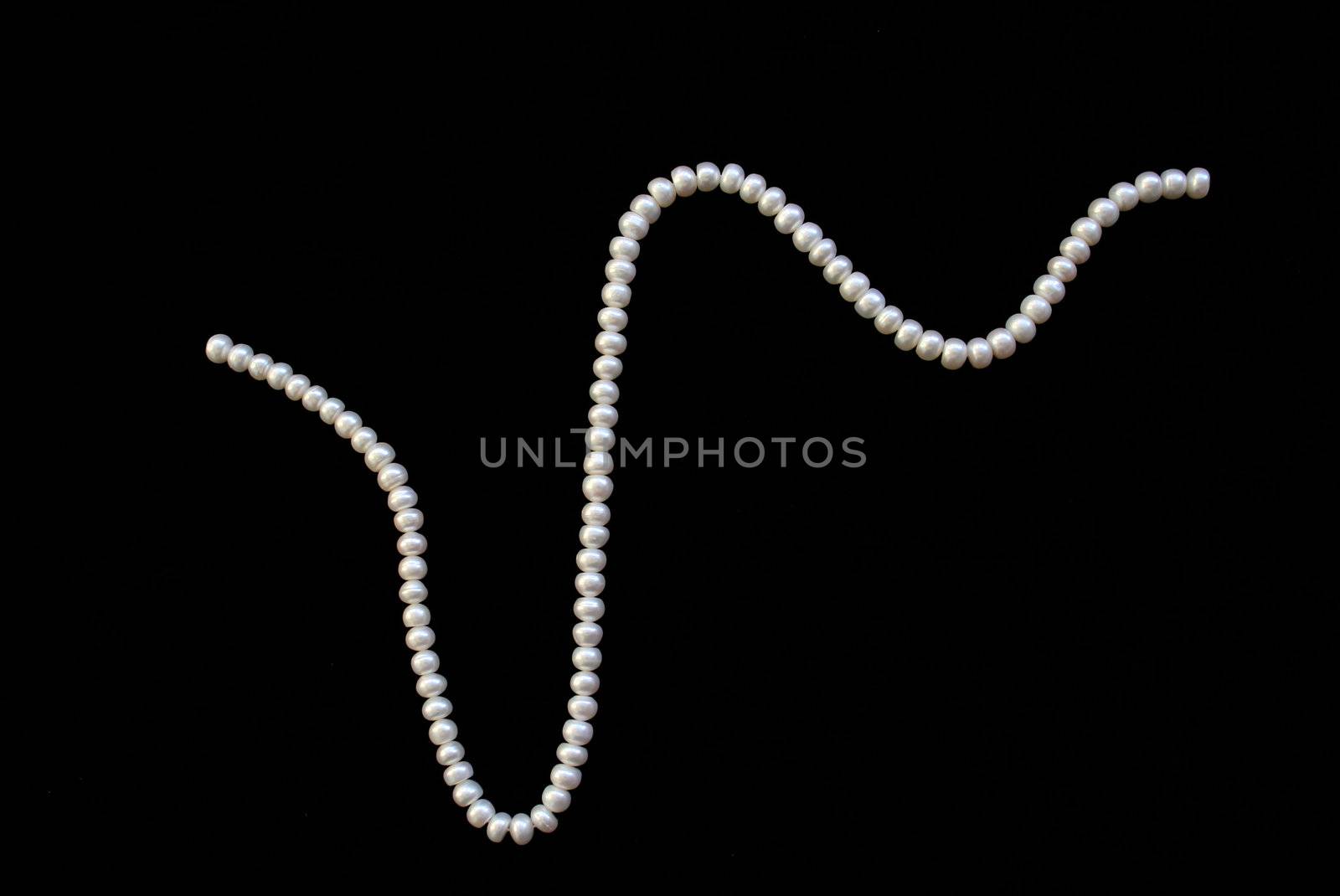 White pearls on the black silk as background 