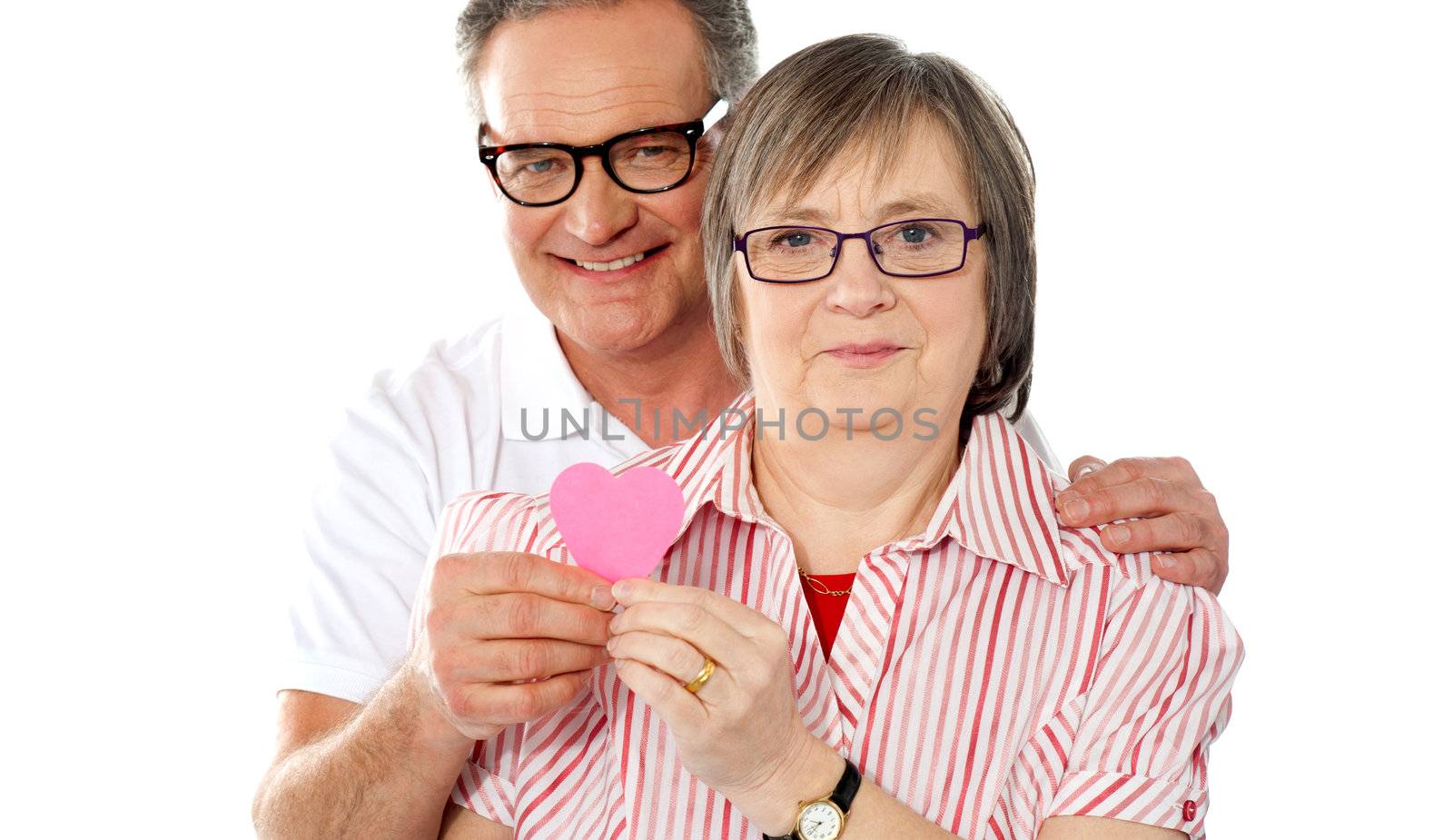 Portrait of a matured smiling couple holding paper heart. Showing to camera
